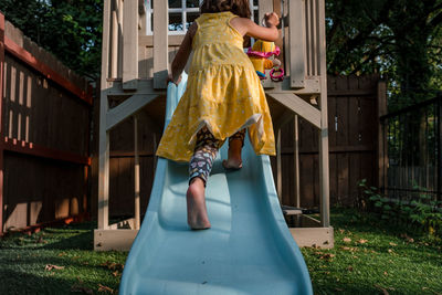 Little girl climbing up a slide in backyard