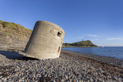 Rock formations on beach against blue sky