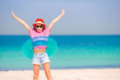 Portrait of girl wearing inflatable ring while standing on beach