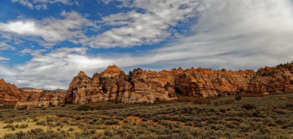 Rock formations on landscape against cloudy sky