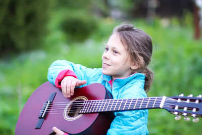 Cute girl playing guitar outdoors