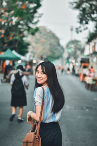 Young woman standing on road in city