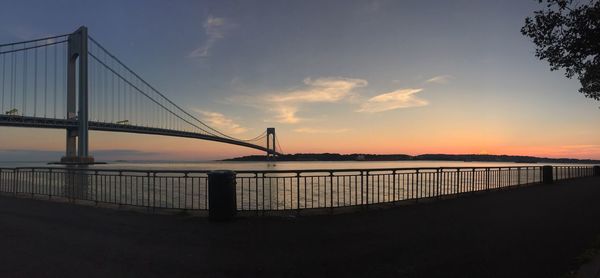 Suspension bridge over river during sunset