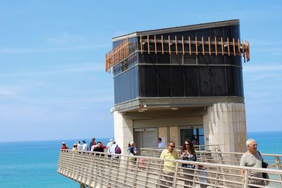 People at observation point by sea against sky