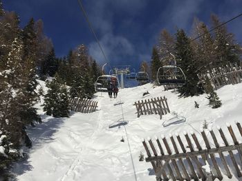 Ski lift over snow covered field against sky