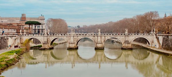 Arch bridge over river against sky