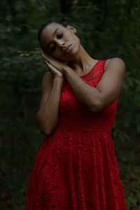 Beautiful woman with eyes closed standing against plants