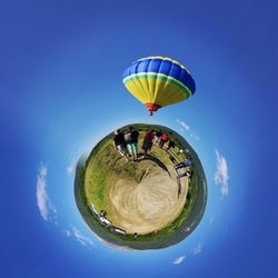 Little planet effect of hot air balloon over people on field against sky