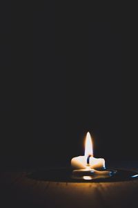 Close-up of burning candle against black background