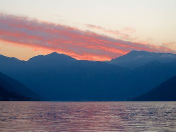 Scenic view of lake by mountains against sky during sunset