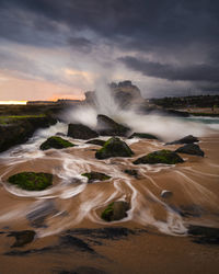 Scenic view of waterfall against sky during sunset