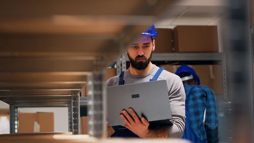 Side view of man using laptop while standing in office