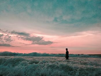 Man standing on field against sky during sunset