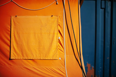 Part of orange tent in front of blue wall