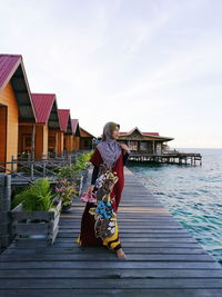 Woman standing in traditional clothing on pier over sea against sky