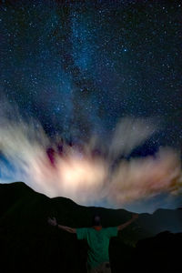 Rear view of man standing against sky at night