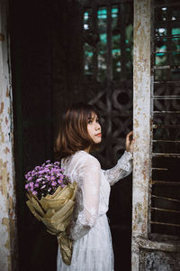 Bride holding bouquet by door