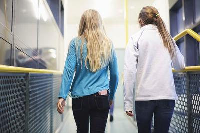 Rear view of girls walking in school corridor