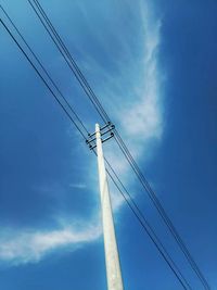 Low angle view of electricity pylon against blue sky