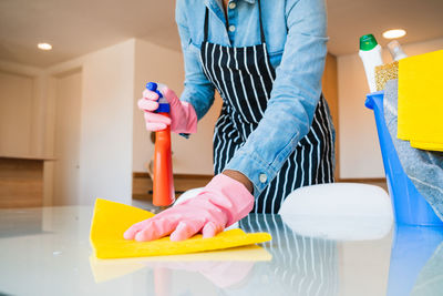 Midsection of woman cleaning floor with cleaner and sponge at home