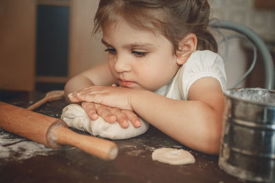 Cute girl sitting at kitchen with dough