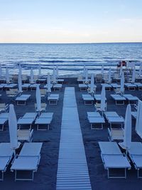 Chairs on beach against clear sky