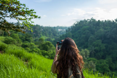 Woman photographing on field against sky