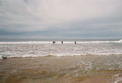 People at beach against sky