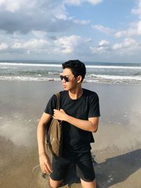 Side view of man standing at beach against sky