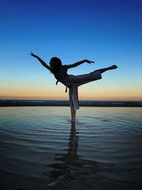 Full length of person paragliding in sea against sky