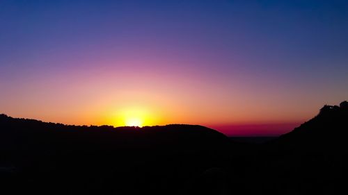 Scenic view of silhouette mountains against romantic sky at sunset