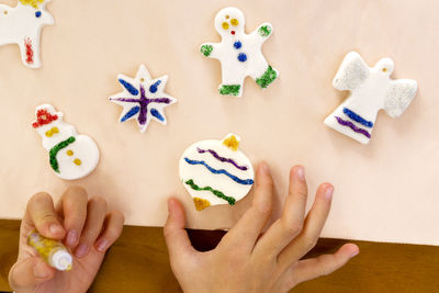 Cropped hand of child icing food on table