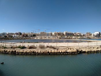 Panoramic view of river and buildings against clear blue sky