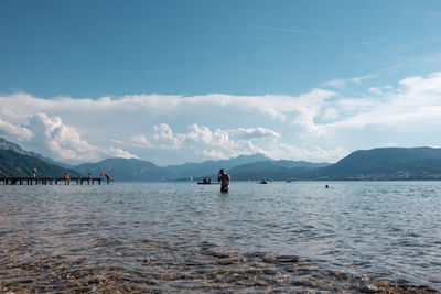 Shirtless man standing in sea against sky