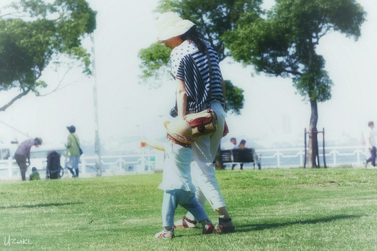 REAR VIEW OF WOMAN STANDING ON GRASS