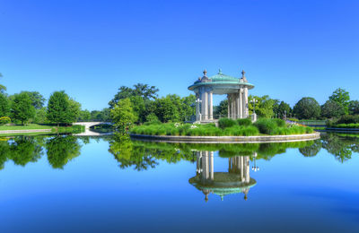 Reflection of building in lake against blue sky