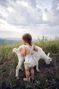 Baby boy playing in the field with a small goat