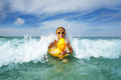 Young woman swimming in sea against sky