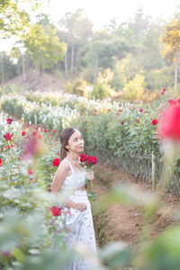 Portrait of young woman standing by plants