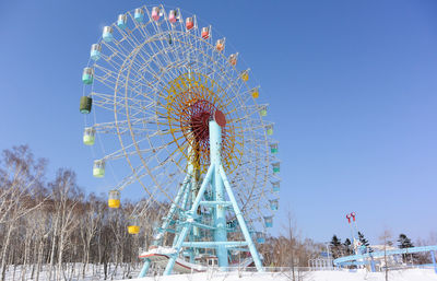 Low angle view of ferris wheel against clear blue sky