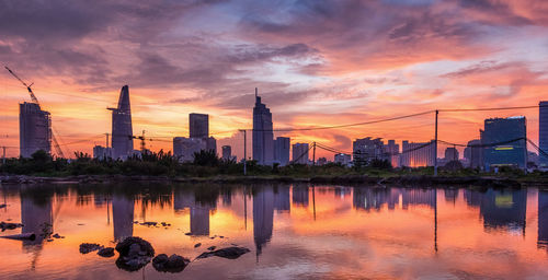 Reflection of city skyline on calm lake during sunset