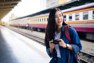 Woman holding camera at railroad station