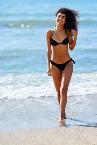 Cheerful young woman wearing black bikini at beach