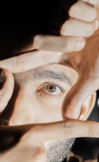 Close-up of man eye through finger frame