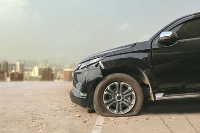 Damaged car on road against sky in city