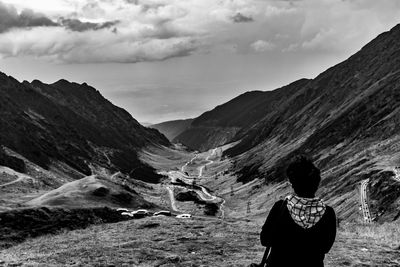 Rear view of man looking at mountains against sky