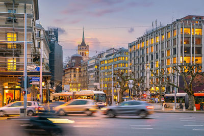 Traffic on city street by buildings against sky