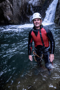 Medium shot of a man in a canyon with a waterfall behind