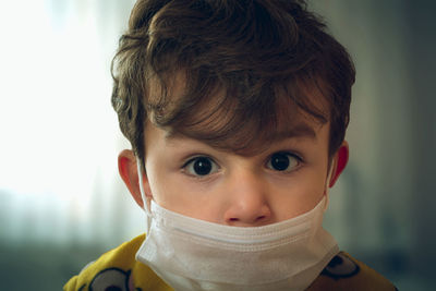 Close-up portrait of cute boy wearing mask at home