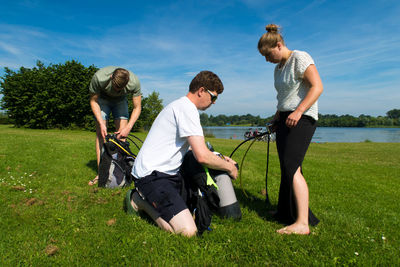 People preparing for scuba diving on grassy field against sky